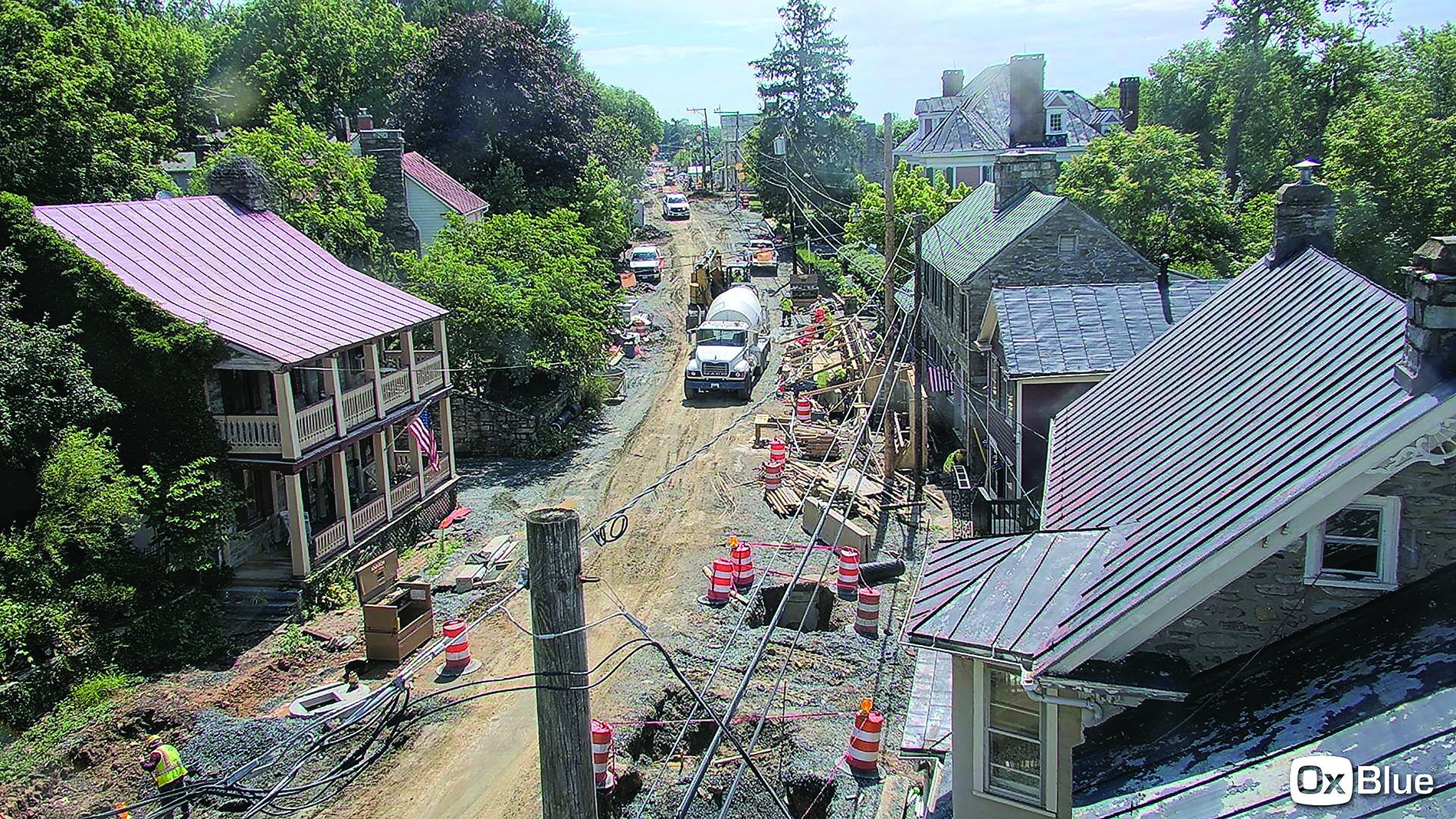 Power lines and trucks on a dirt road lined by historic houses. Image by Town of Hillsboro.
