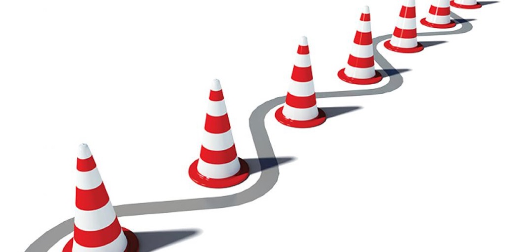 Striped traffic cones by gray curve. Image by iStock.