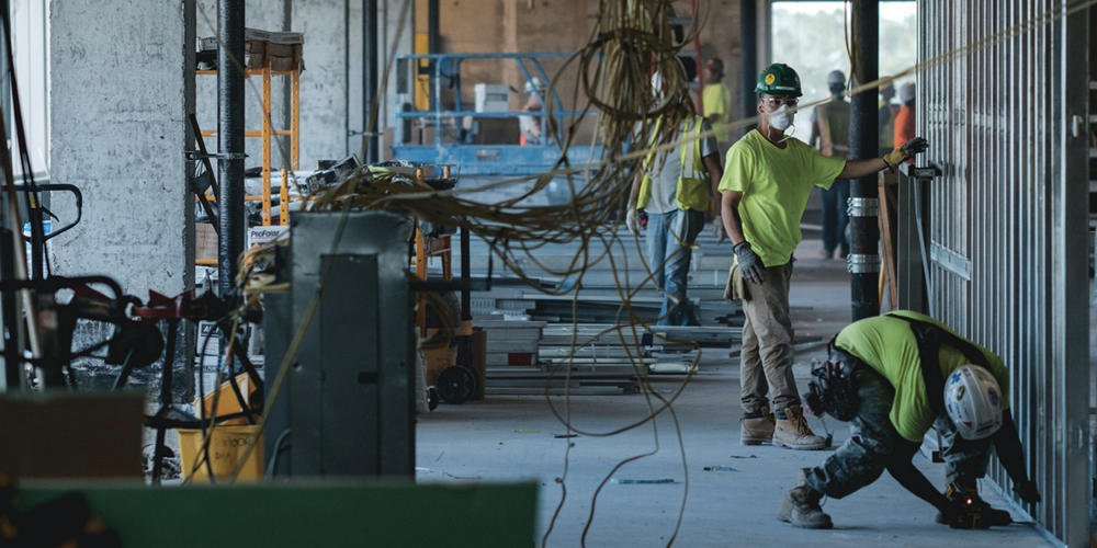 Workers in a concrete building with wires. Image by Procore.