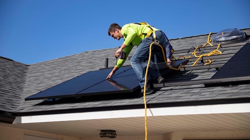 A worker installs a solar panel on a home's roof. Photo by Raze Solar on Unsplash