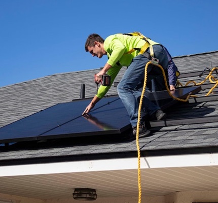 A worker installs a solar panel on a home's roof. Photo by Raze Solar on Unsplash