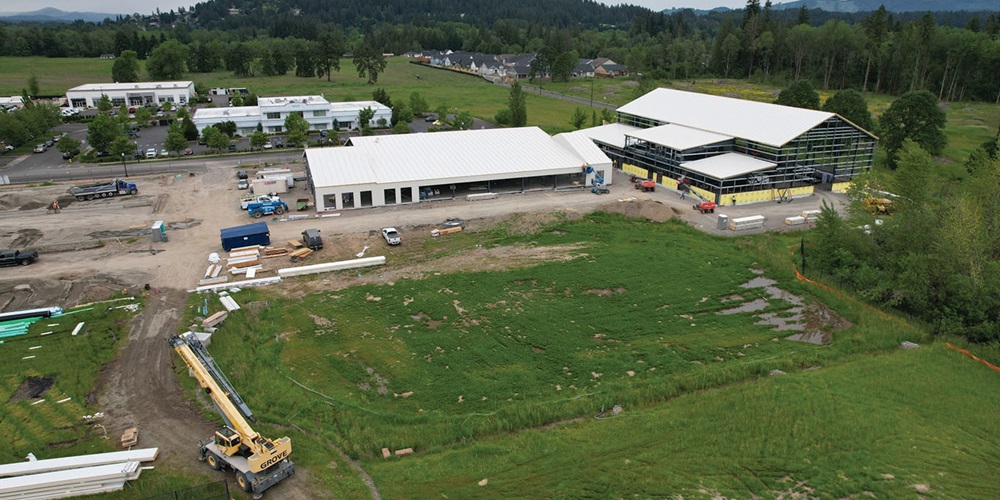 Large white buildings amid green fields and hills. Image by Northwest Line JATC.