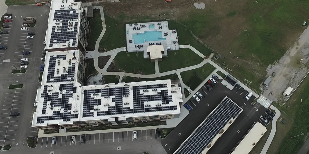 Aerial image of a building with solar panels, parking lot, and grass. Image by Day & Night Solar.