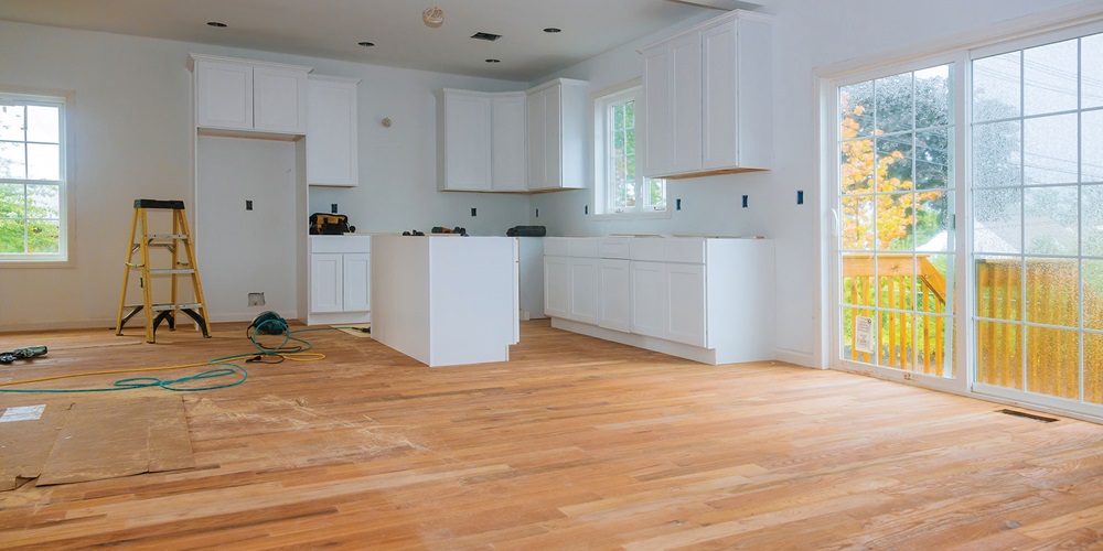 White kitchen with a hardwood floor and a stepladder. Image by Shutterstock / ungvar.