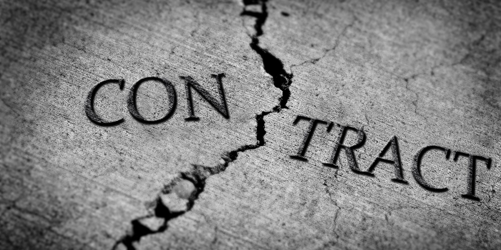 Cement stamped with the words contract cracked in half. Image by Shutterstock / Lane V. Erickson.