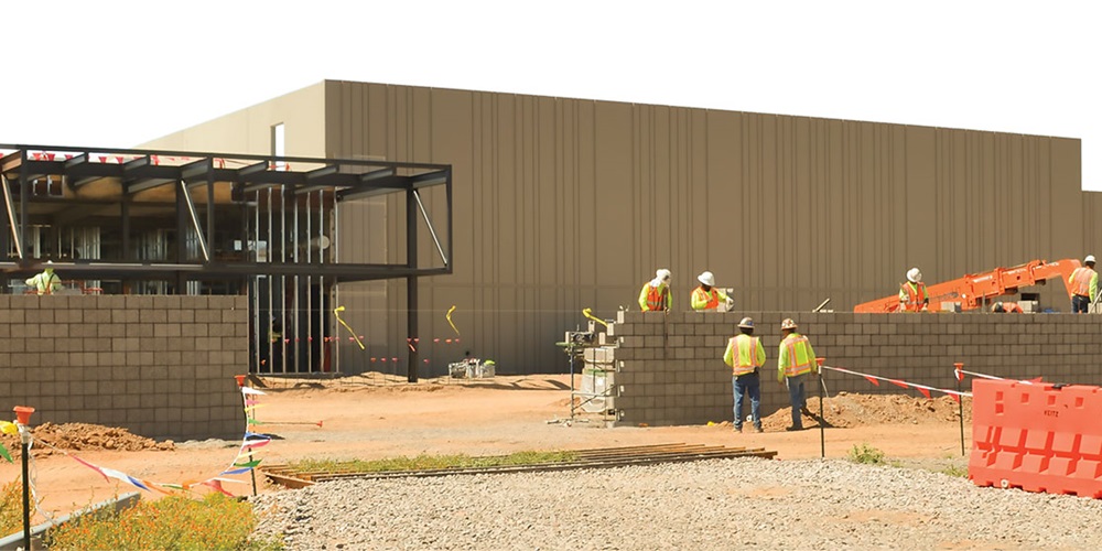 Workers outside a tan building. Image by The Weitz Co.