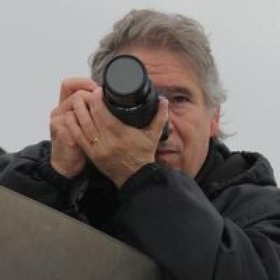 Stephen Carr headshot. A man with gray hair holding up a camera.