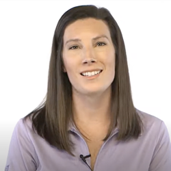 A woman in a purple shirt with brown hair smiles at the camera