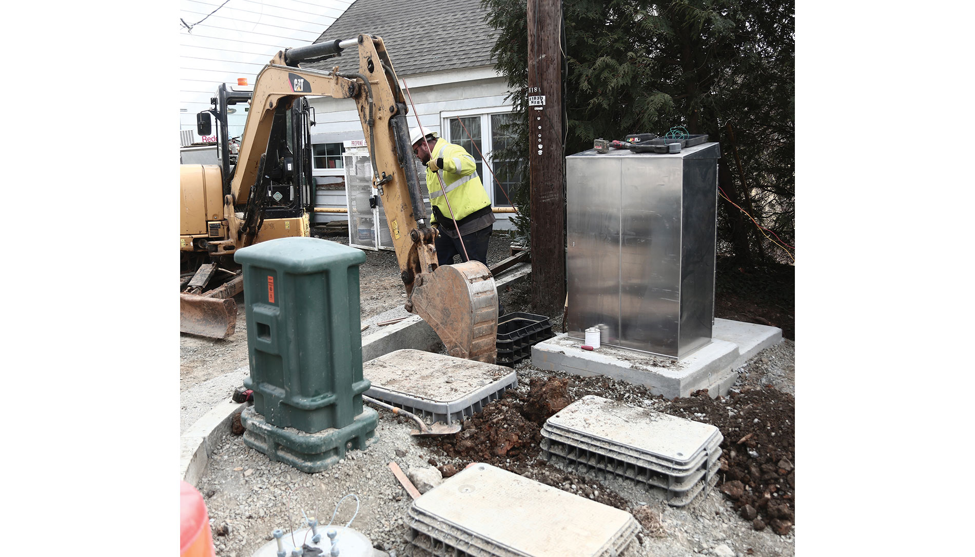 A worker and an excavator by utility boxes. Image by Town of Hillsboro.