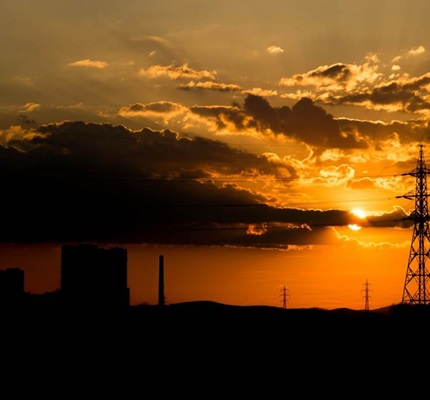 Buildings, a communication tower and dark clouds silhouetted against a blue and orange sunset. Image by iStock.