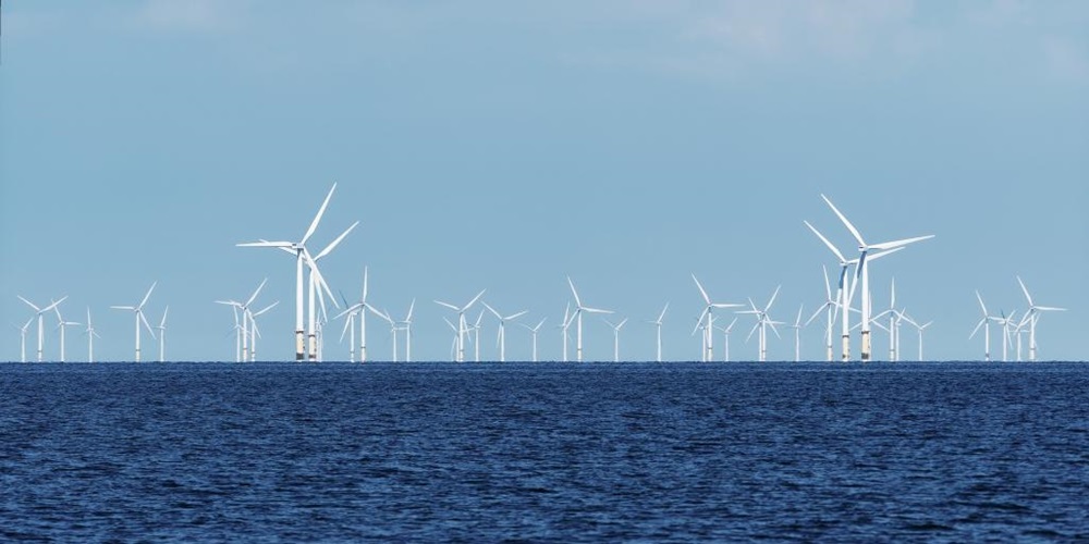 Wind turbines atop a blue sea against a blue sky. Image by Pixabay / Aitoff.