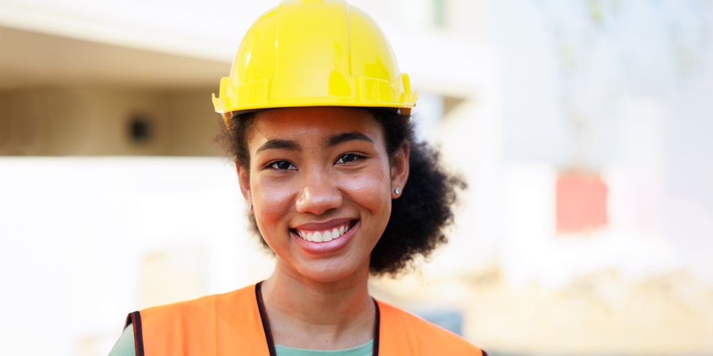 A black woman wearing a hard hat and hi-vis vest. Women in construction make up only 14% of the workforce.
