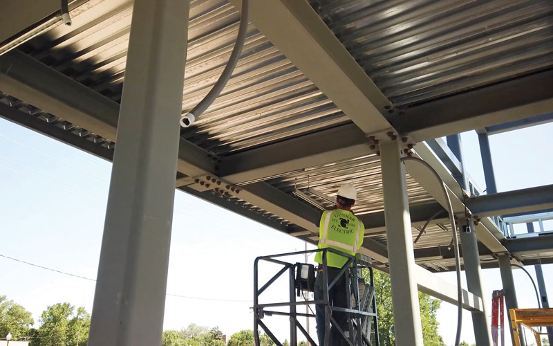 Worker  in a cherry picker installing lights underneath a platform