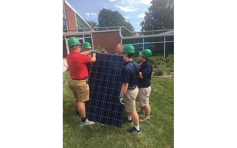 Students and instructors working with a solar panel