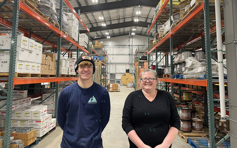 Woman and her teenage son standing in a wearhouse