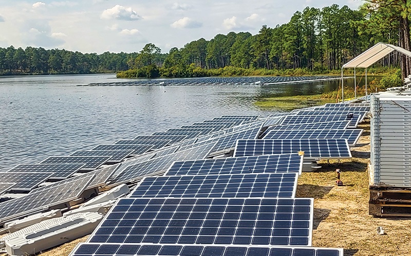 solar panels next to lake / Powering the Army / The system consists of 2,700 PV panels with a string inverter. Womack Electric assembled the array on-shore and deployed it in a shallow area of the lake.