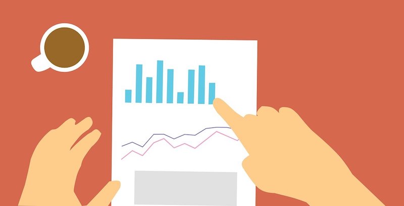 A hand points at a paper with graphs on it